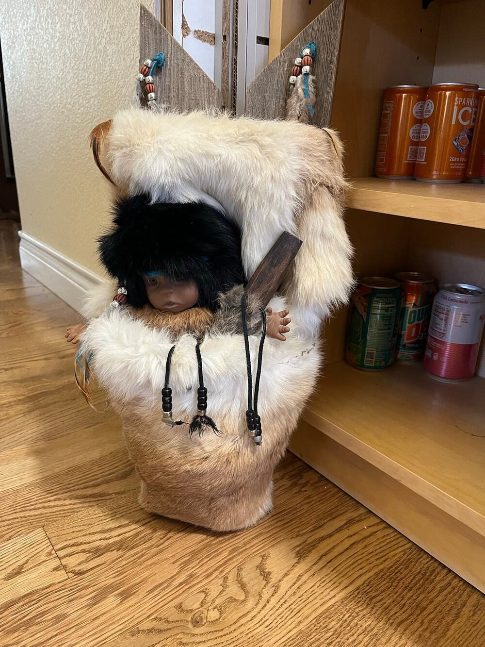 Native American-style baby doll placed inside a fur-trimmed cradleboard